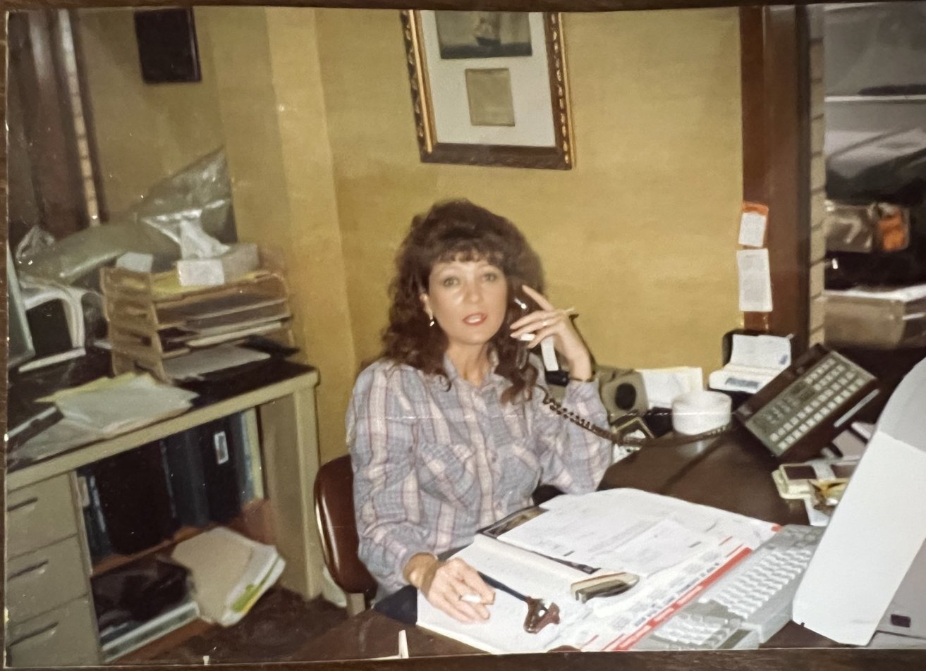 Snapshot of a Stover and Crouch team member answering the phone at a paper-covered desk in the 1980s office